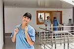 Laughing doctor standing in the hallway while touching her stethoscope