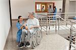 Nurse smiling and kneeling beside old women sitting in wheelchair