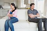 Two people sitting on the couch with crossing arms and falling quiet in the living room