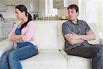 Two people ignore each other while sitting in the living room on the couch