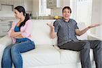 Two people sitting on the couch in the living room fighting
