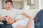 Pregnant woman touching her belly with husband lying on sofa