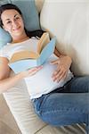 Young pregnant woman relaxing on the couch and reading a book