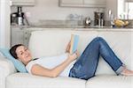 Pregnant woman reading on couch in living room