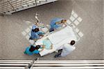 Three nurses and one doctor pushing one patient in a bed in hospital corridor