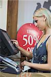 Woman is standing behind the counter of the shop while typing