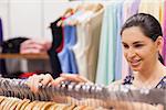 Woman sorting clothes on rail and smiling