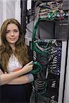 Young woman holding usb cable in front of rack mounted servers