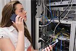 Woman working on servers with tablet pc on the phone in data center