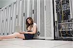 Woman sitting on floor working on laptop in data center