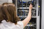 Woman fixing wires of servers in data center