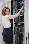 Smiling brunette fixing wires of servcer at the data center