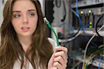 Woman looking confused at wire of server in data center