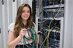 Happy woman holding server wires in data center
