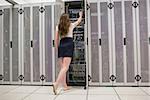 Woman standing in the hallway in data center and fixing wires