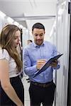 Technicians talking in data center while looking at a clipboard