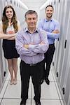 Smiling technicians standing in data center with arms crossed