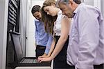 Three technicians looking at laptop in data center