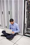 Technician looking at his laptop while doing maintenance on servers on the floor