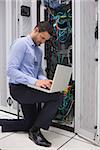 Concentrated technician doing data storage with laptop