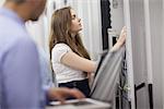 Technicians working on servers with laptop in data center