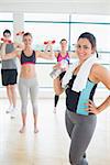 Smiling woman at front of aerobics class with water and towel