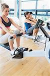 Man and womenusing the row machines in fitness studio