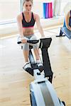 Woman changing settings on row machine in fitness studio