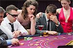 Man losing at poker table with woman comforting him in casino