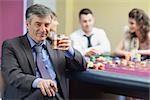 Man drinking whiskey at roulette table in casino