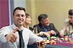 Man giving thumbs up and holding whiskey glass at roulette table
