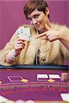 Woman in a casino sitting at table and showing cards