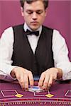 Dealer shuffling the deck of cards at poker table