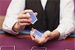 Dealer shuffling deck of cards while sitting at table of a casino