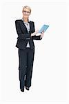 Smiling businesswoman standing while holding and using tablet pc