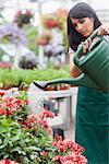 Woman watering plants in garden centre