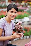 Woman holding a flower while smiling outside the garden centre