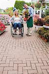 Garden center employee holding a plant and woman in wheelchair