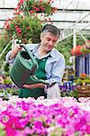 Smiling man watering flowers in garden centre