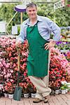 Man leaning on a spade while smiling in garden center