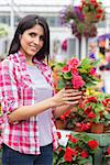 Smiling woman in garden center holding a flower