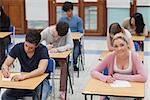 Students sitting at the exam room while concentrating with one looking up and smiling