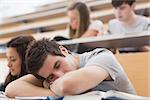 Student sitting at the lecture hall leaning on the table sleeping