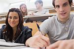 Students sitting at the desk smiling at the lecture hall