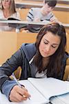 Woman sitting at the lecture hall while writing