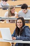 Girl sitting at the lecture hall smiling with her laptop
