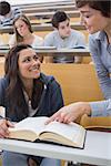 Lecturer explainging to student in lecture hall with large book