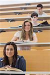 Students sitting while smiling in lecture hall in different rows