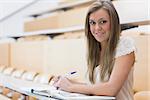 Girl sitting while smiling at the lecture hall making notes