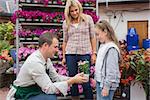 Garden center worker giving a flower to child while her mother standing next to her